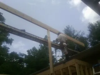 Carpenter setting a ridge beam over a new addition frame — Ice Dam Removal by Roofing Brothers in Bronwood