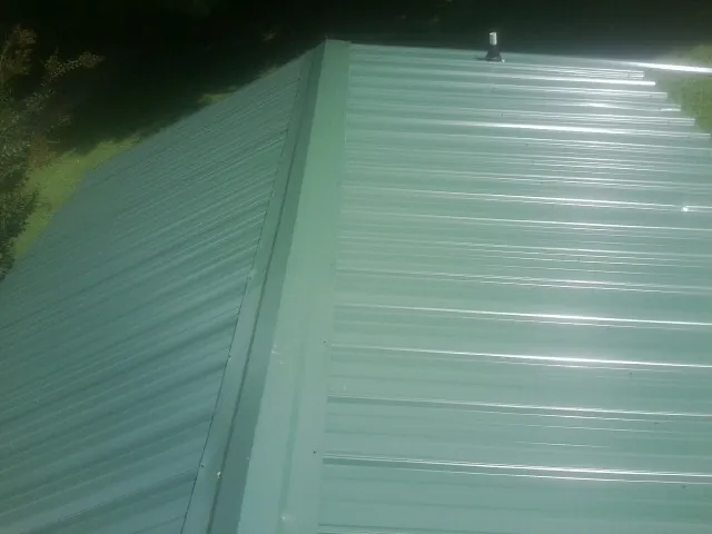 New green metal panels meeting at the ridge of a roof — Flat Roof Repair work by our crew in Bronwood