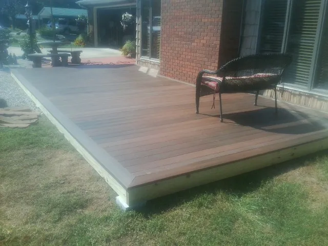 New wood deck and wicker chair beside a brick house in Bronwood