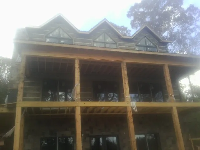 Dormers and porch framing on a large log home under construction — Roof Coating work by our crew in Bronwood