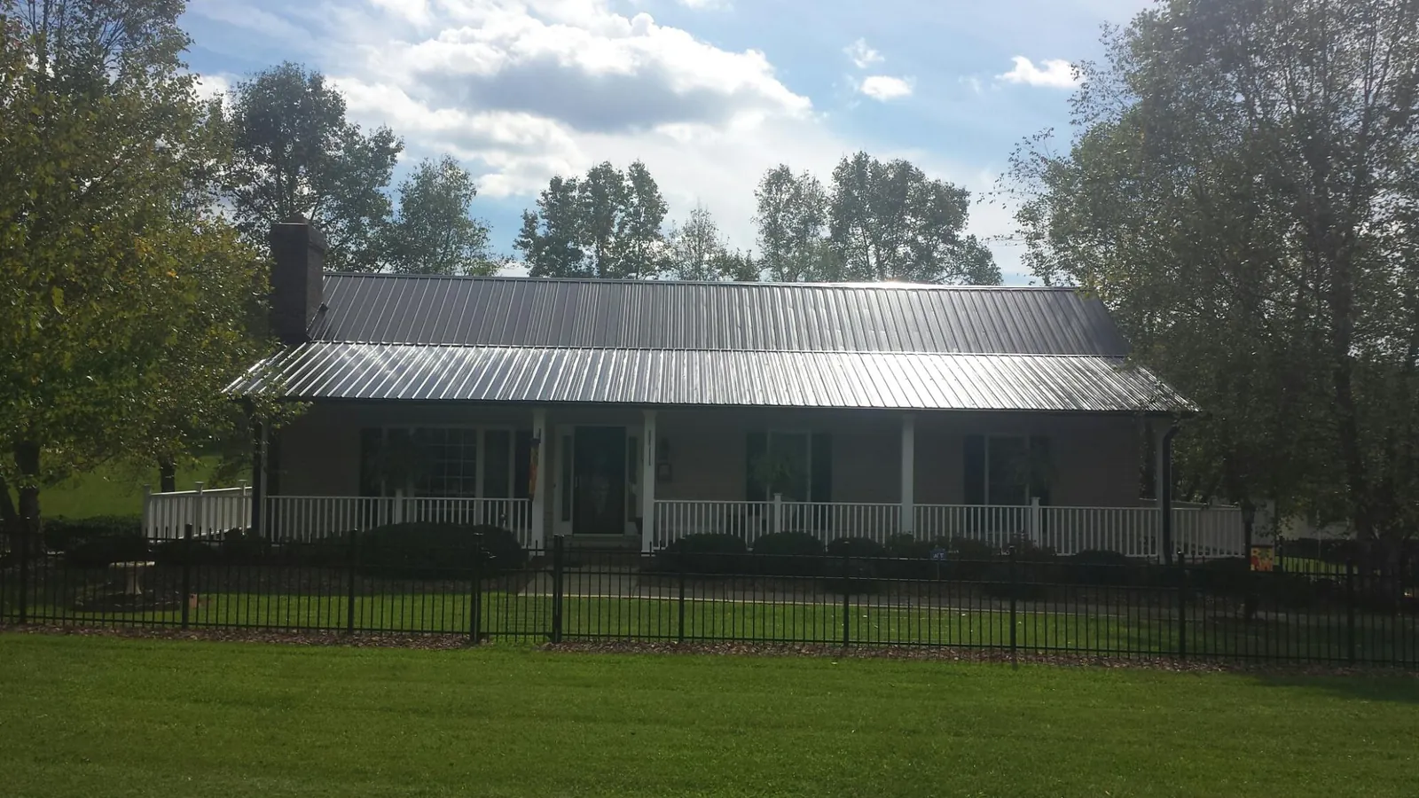 Gray metal roof on a brick ranch with a full width front porch — Gutter Guard Installation work by our crew in Bronwood