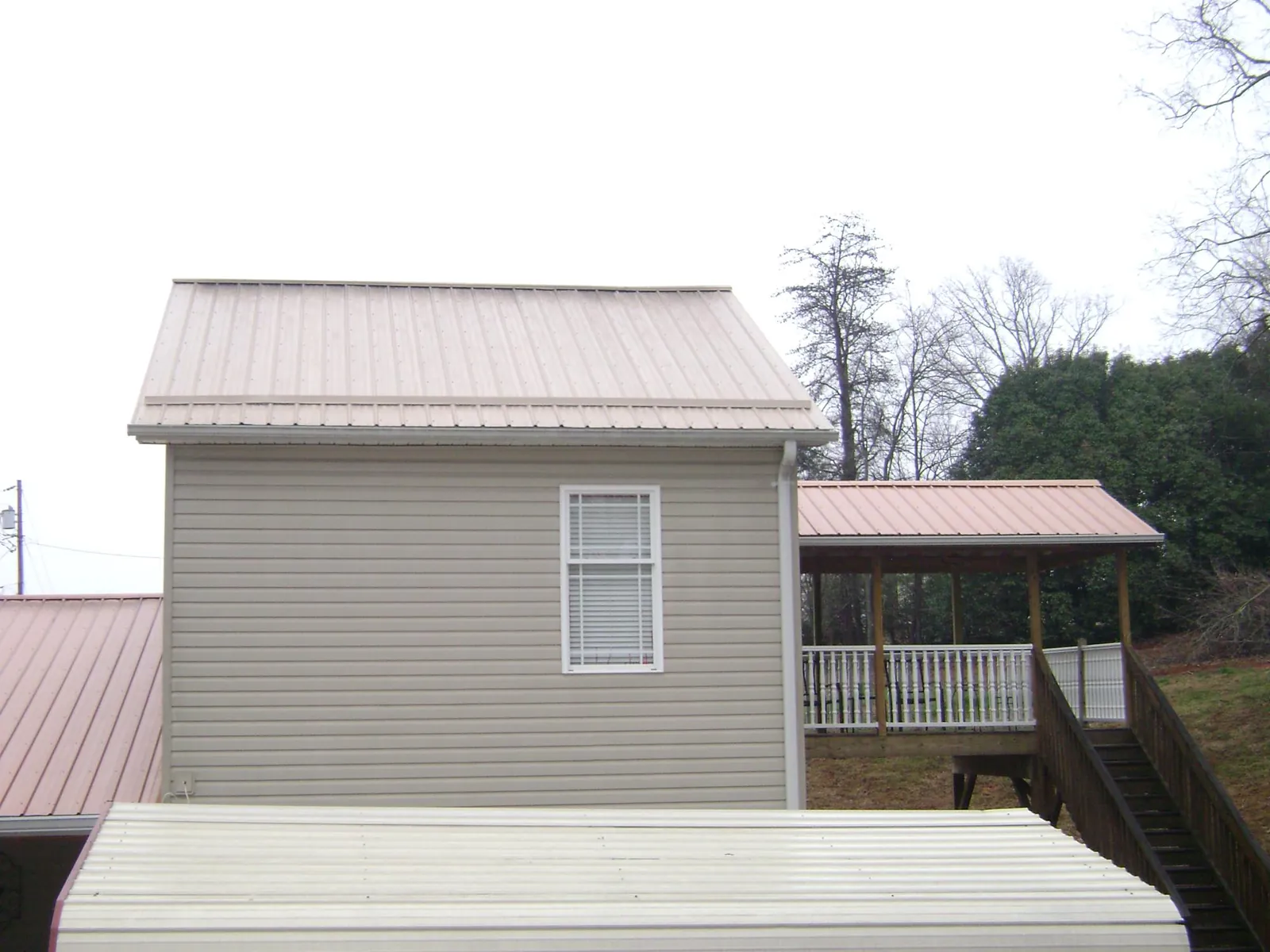 Tan metal roofs on a two story addition and attached porch, from a Roof Replacement job in Bronwood