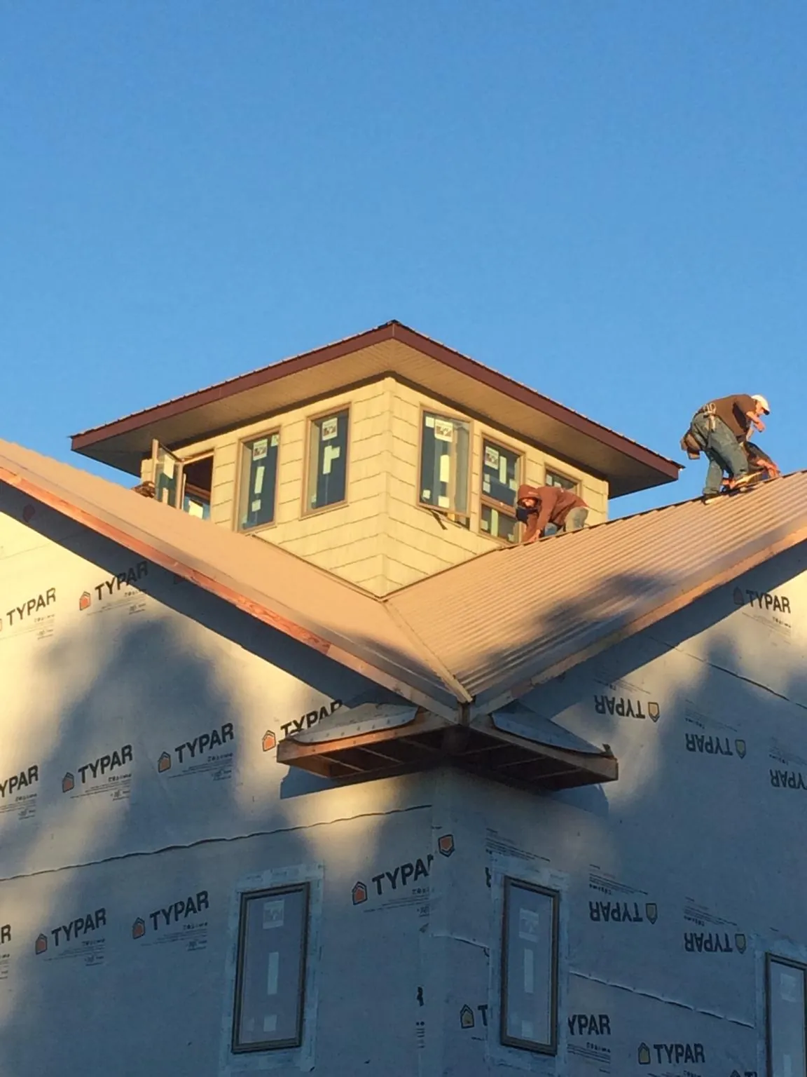 Roofers working around a rooftop cupola on a new metal roof at sunset — Roof Waterproofing in Bronwood by Roofing Brothers